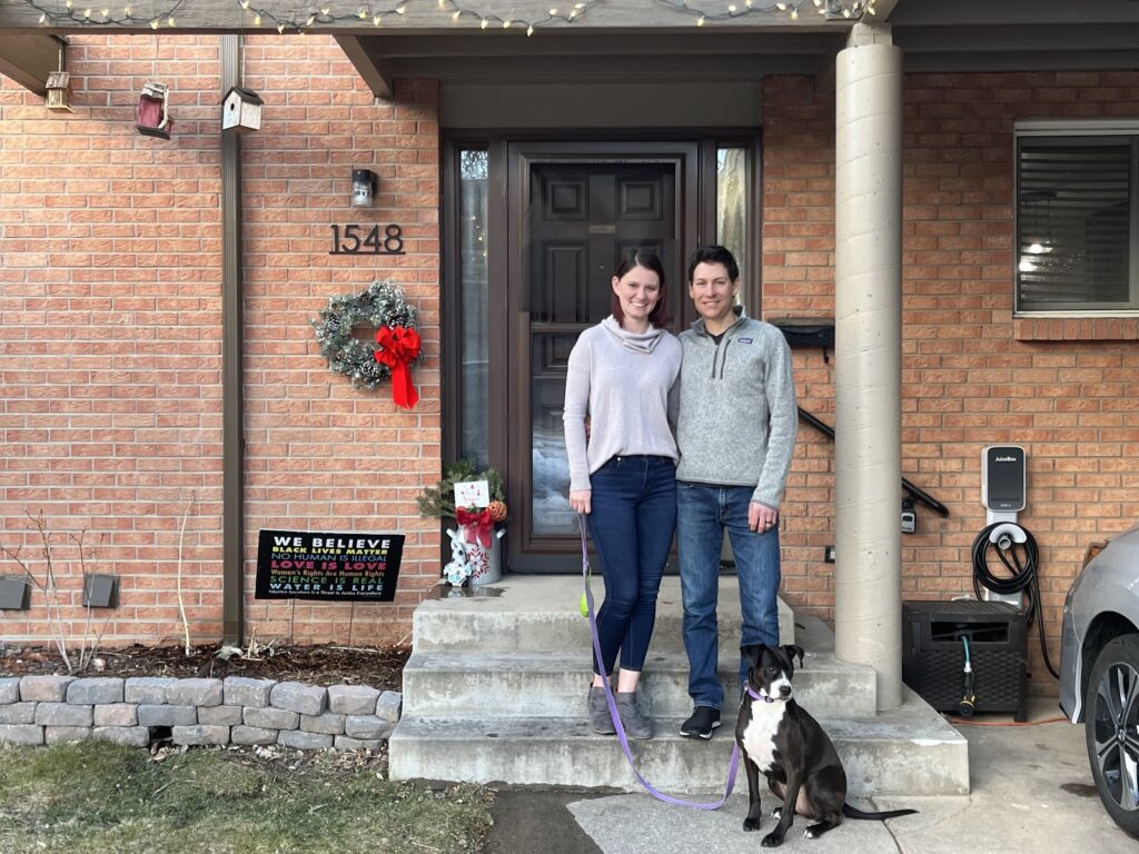 The couple in front of their fully electric home (and next to their new EV charger!)